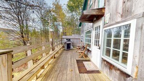 Une terrasse en bois avec un barbecue, des chaises et une clôture en bois.