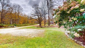 Un paysage rural avec un chemin de gravier, des arbres et un bâtiment en arrière-plan.