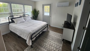 Une chambre à coucher avec un lit, une télévision, une porte et une fenêtre.
