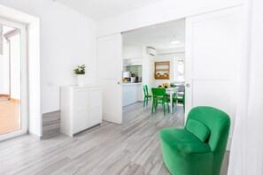 Une cuisine moderne avec des meubles blancs, un coin repas avec des chaises vertes et un espace lumineux et ouvert.