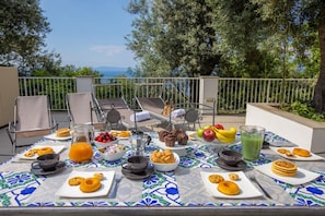 Una mesa servida con alimentos para el desayuno en una terraza con vistas a un paisaje pintoresco.