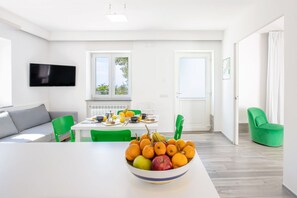 Una sala de estar moderna con comedor, un televisor de pantalla plana y un cuenco de fruta sobre la mesa.