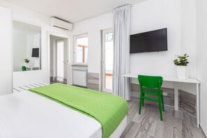 Una habitación de hotel con cama, escritorio, silla, televisión y ventana.