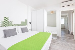 Une chambre d’hôtel moderne avec un lit, un banc, une porte et un couloir.
