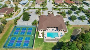 An aerial view of a residential area with a large tennis court, a swimming pool, and a house with a covered patio. - Motorhome Pad - Mt. Olive Shores North (Polk City)