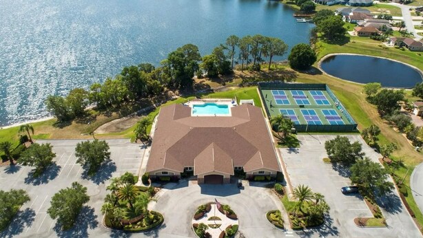 An aerial view of a property with a swimming pool, tennis courts, and a large parking lot. - Motorhome Pad - Mt. Olive Shores North (Polk City)