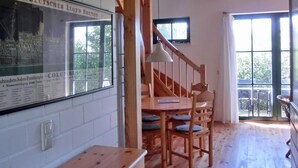 A wooden interior with a staircase, a dining area, and a large window.