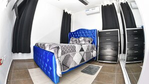 A bedroom with a blue bed, a ceiling fan, a black wardrobe, and a grey rug. - Apartamento EN LAS Carreras Centro DE LA Ciudad (Santiago)