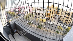 A balcony with a curved railing overlooking a street with buildings and cars. - Apartamento EN LAS Carreras Centro DE LA Ciudad (Santiago)