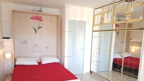 Une chambre à coucher avec un lit, une table de chevet, un miroir et une couvre-lit rouge.