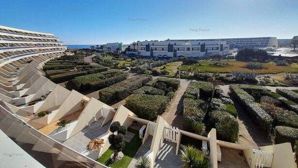 A modern hotel with a curved facade, landscaped gardens, and a clear view of the sea. - Apartement Intense (LE CAP D AGDE)