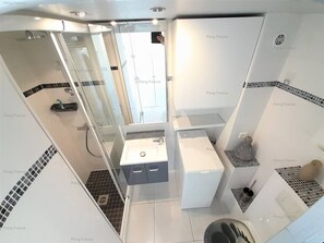 A modern bathroom with a glass shower enclosure, a white sink, and a toilet.