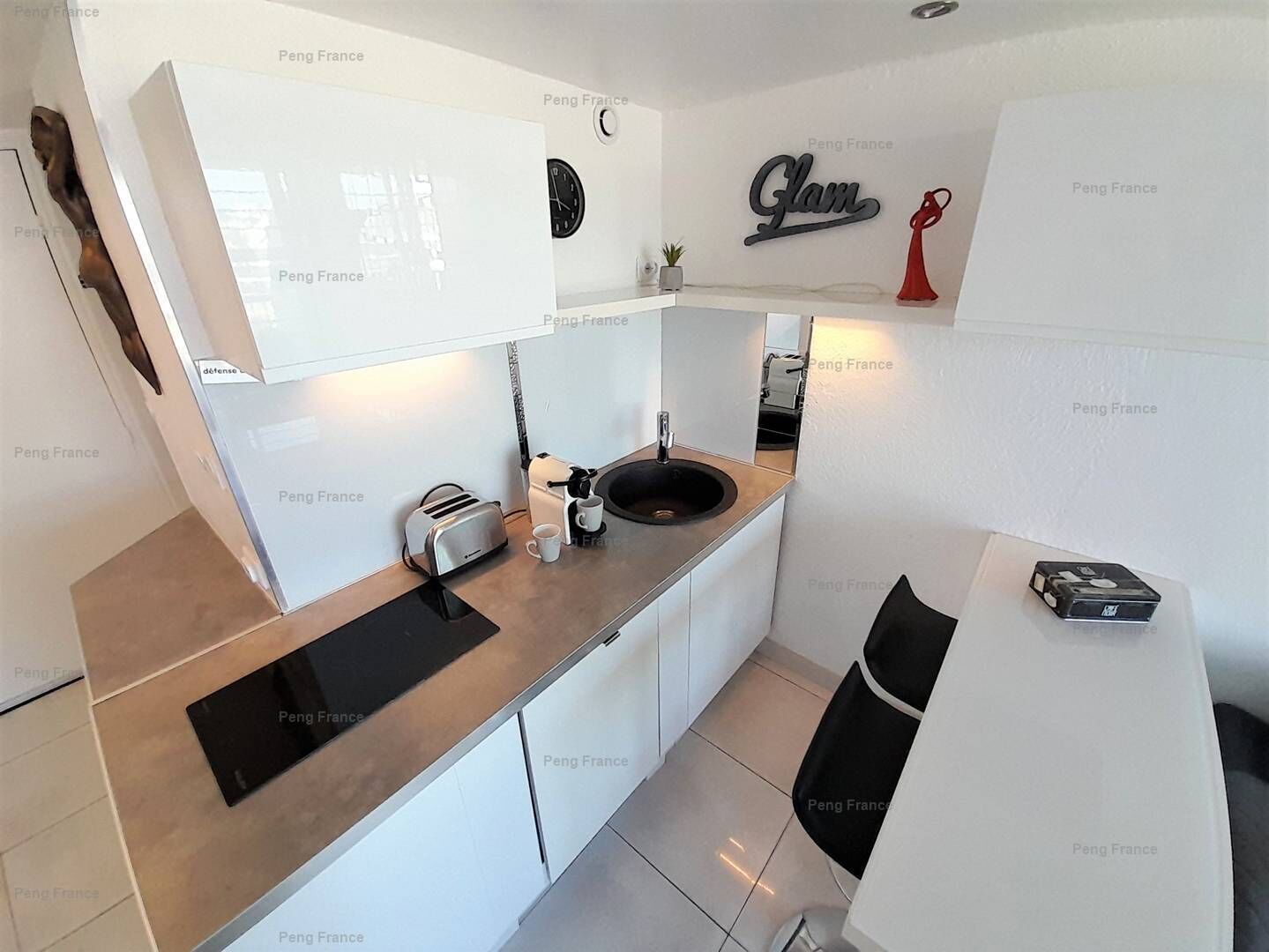 A modern kitchen with a built-in oven, a coffee maker, and a sink.