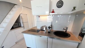 Una cucina moderna con piano cottura integrato, lavandino e orologio a parete.