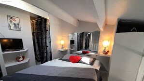 Una camera d'albergo moderna con un letto grande, lampade sui comodini, una TV e un armadio.