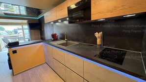 Uma cozinha moderna com armários de madeira, bancada preta e forno embutido.