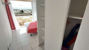 Een kamer met een bed, een tafeltje en uitzicht op zee.