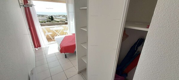 A room with a bed, a small table, and a view of the sea.