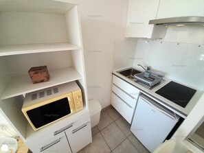 Een koelkast, een microgolfoven, kookgerei, borden en bestek