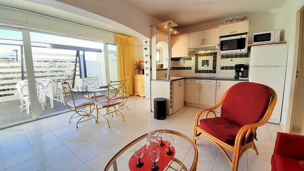 A modern kitchen with a microwave, oven, and coffee maker. There is a dining area with a table and chairs, and a balcony with a view. - Villa COCO GIRL (LE CAP D AGDE)