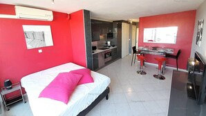 A modern hotel room with a bed, a desk, and a kitchenette. - Apartment "PEPPERONI" (LE CAP D AGDE)