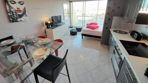 A modern apartment with a dining area, kitchenette, and a bed with a city view. - Apartment "PEPPERONI" (LE CAP D AGDE)