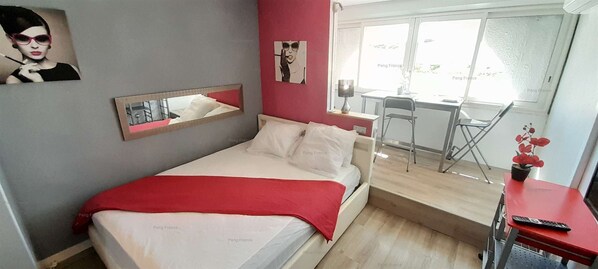 A bedroom with a bed, a desk, a chair, and a window.