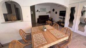 A dining area with a table, chairs, and a television in the background.