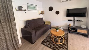 A living room with a sofa, a TV, a small table, and decorative items on the walls.