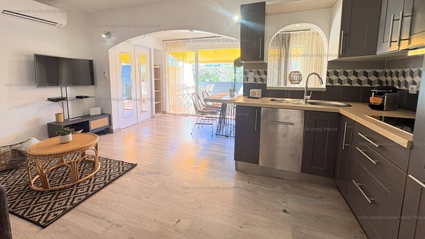 A modern kitchen with dark cabinets, a built-in oven, and a dining area with a table and chairs.
