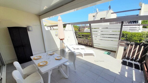 A patio with a table set for dining, white chairs, and a grill. - Villa "Séduction" (LE CAP D AGDE)