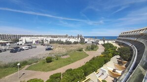 Un hotel costero con aparcamiento, un edificio grande al fondo y vistas al mar.