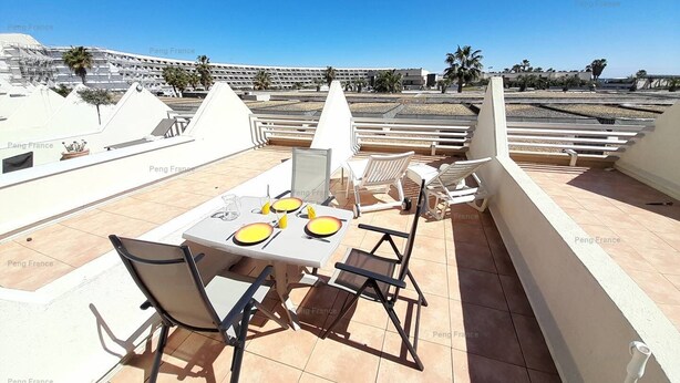 A rooftop terrace with a table set for two, chairs, and a view of a cityscape. - Studio 'DEVIL or EDEN" (LE CAP D AGDE)