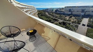 Ein Balkon mit gebogener Geländer, mit Blick auf eine Stadtlandschaft aus Gebäuden und Grünflächen.