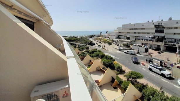 Un quartiere residenziale con vista sul mare, una strada con auto parcheggiate e palazzi con balconi.