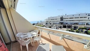 Un balcone con tavolo e sedie, un divano e vista su edifici e mare.