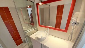 Un bagno moderno con cabina doccia in vetro, un lavandino bianco e uno schienale in piastrelle rosse, e una lavatrice a incasso.