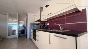 Une cuisine moderne avec des meubles blancs, un plan de travail noir et un pare-feu violet.