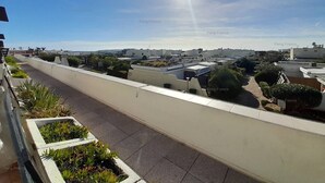 Une terrasse sur le toit offrant une vue dégagée sur les bâtiments environnants, une allée pavée et quelques espaces verts.