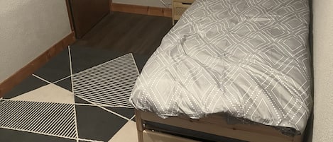 A small, neatly arranged bedroom with a bed, bedside table, and a nightstand.