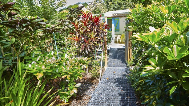 Un chemin de jardin qui mène à une construction à la façade bleue et blanche.