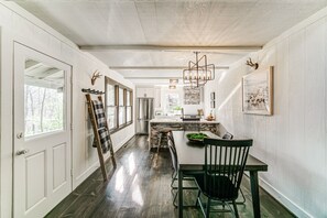 Enjoy meals in this dining area with a long table set for two, a high ceiling, and a stone accent wall.