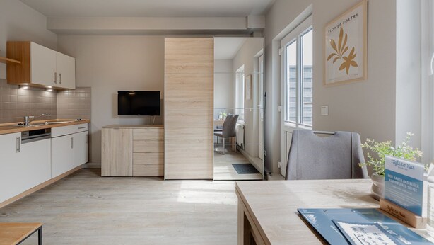Une cuisine moderne équipée d’un téléviseur, de meubles en bois et d’un coin repas avec une table et des chaises.