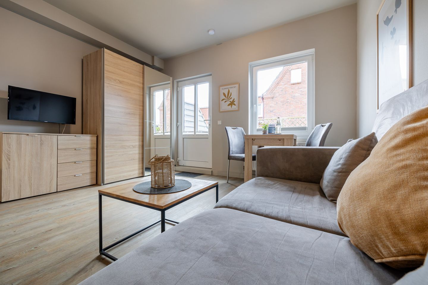 Un salon moderne comprenant un canapé, un téléviseur, un meuble en bois et un coin repas avec une table et des chaises.