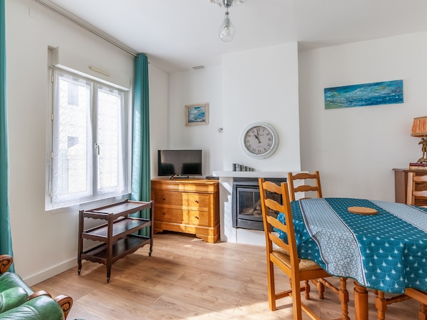 Una sala de estar acogedora con un mueble bajo de madera para el televisor, una chimenea y una mesa de comedor con sillas.