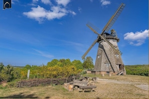 Eine Windmühle mit traditioneller Bauweise, ein Holzgebäude und ein klarer Himmel.