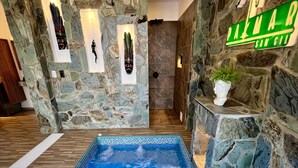 A stone-walled bathroom with a spa tub, a shower, and a sign reading "PAKAR SAN GIL". - Palmar San Gil  (San Gil)