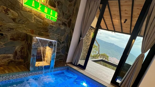 A stone-walled room with a pool, a sign reading "PAMAR," and a view of the mountains through a glass door. - Palmar San Gil  (San Gil)