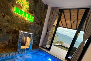 A stone-walled room with a pool, a sign reading "PAMAR," and a view of the mountains through a glass door. - Palmar San Gil  (San Gil)