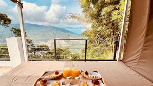 A breakfast tray with pancakes, fruit, and orange juice on a balcony overlooking a mountainous landscape. - Palmar San Gil  (San Gil)